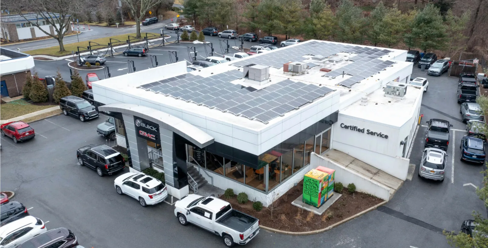 Aerial view of a commercial auto dealership with a full rooftop solar array and on-site energy storage